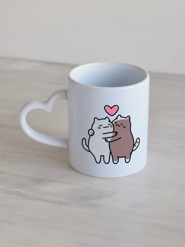 Valge 330ml südamesangaga kruus, kaks kallistavat kassi ja roosa süda.